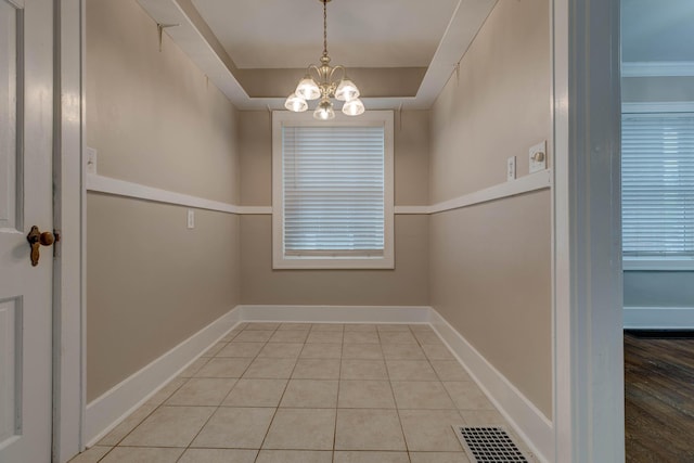 unfurnished dining area featuring a chandelier, tile patterned flooring, and baseboards