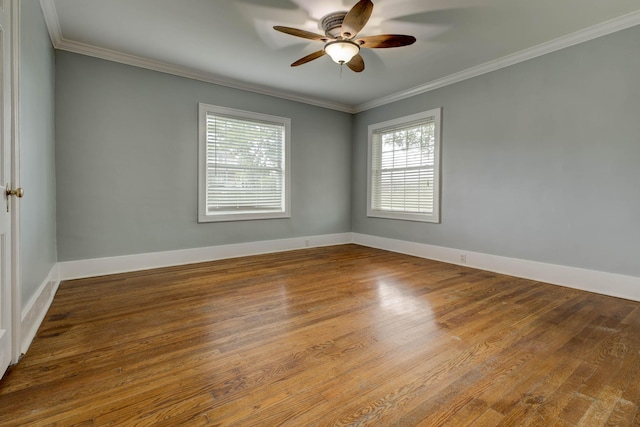 spare room featuring healthy amount of natural light, ceiling fan, wood finished floors, ornamental molding, and baseboards