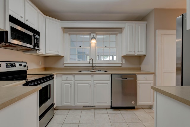 kitchen featuring appliances with stainless steel finishes, a sink, white cabinets, light tile patterned floors, and light countertops