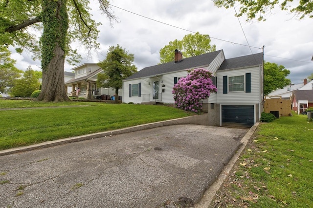 view of front facade featuring driveway, a chimney, a garage, and a front yard