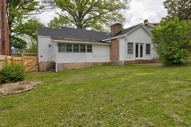 back of house with entry steps, a chimney, and a gate