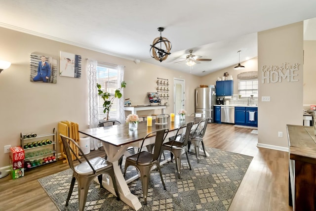 dining room with ceiling fan, light wood finished floors, baseboards, and vaulted ceiling