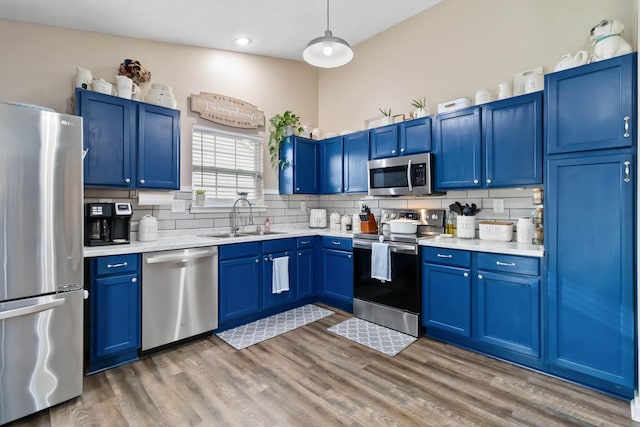 kitchen with stainless steel appliances, a sink, blue cabinets, and recessed lighting