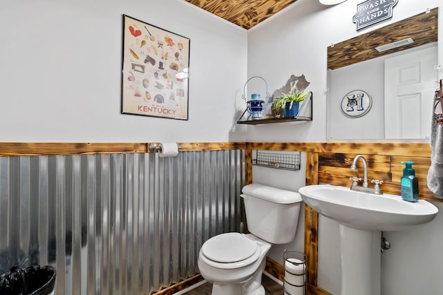 half bathroom featuring toilet and a wainscoted wall