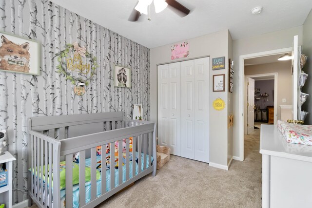 bedroom featuring carpet, a closet, a nursery area, baseboards, and ceiling fan