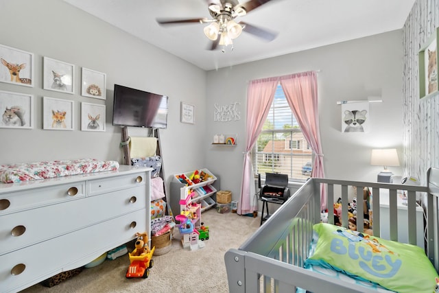 carpeted bedroom featuring a crib and a ceiling fan