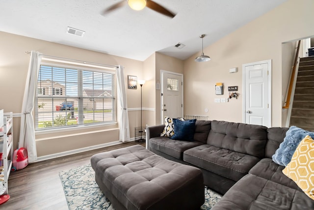 living area with vaulted ceiling, ceiling fan, wood finished floors, stairway, and baseboards