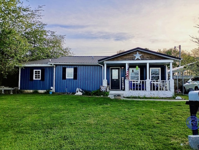 view of front facade featuring a front yard, a porch, board and batten siding, and metal roof