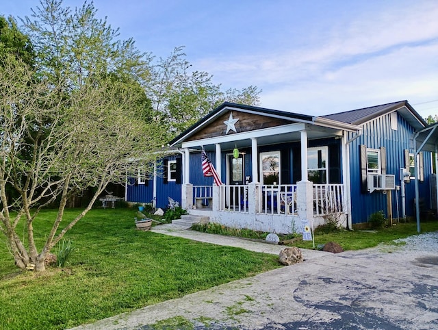 view of front of house with covered porch, a front lawn, board and batten siding, and metal roof