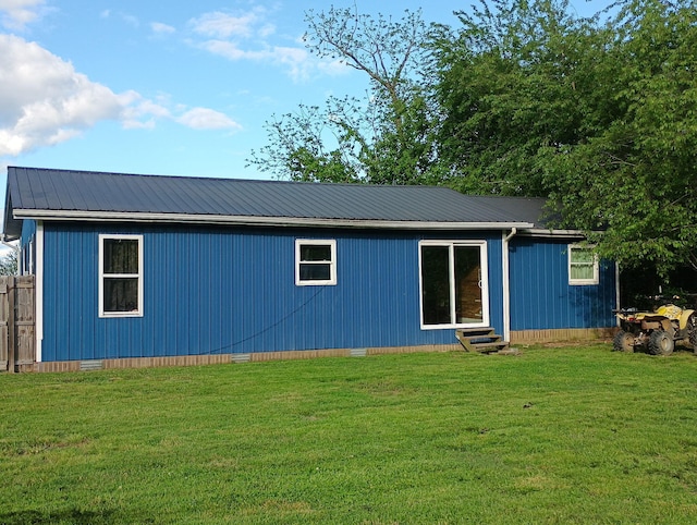rear view of property featuring crawl space, entry steps, metal roof, and a yard