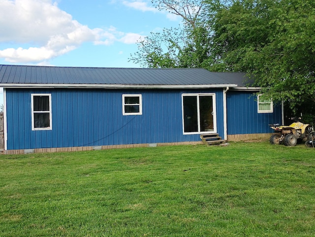back of house featuring entry steps, crawl space, metal roof, and a yard