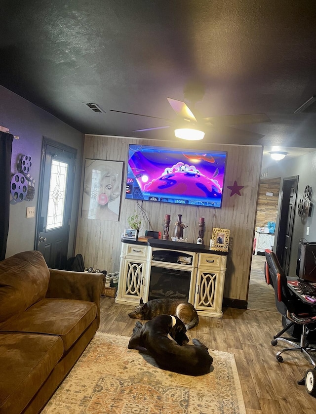 living area with wood-type flooring, a textured ceiling, and wood walls