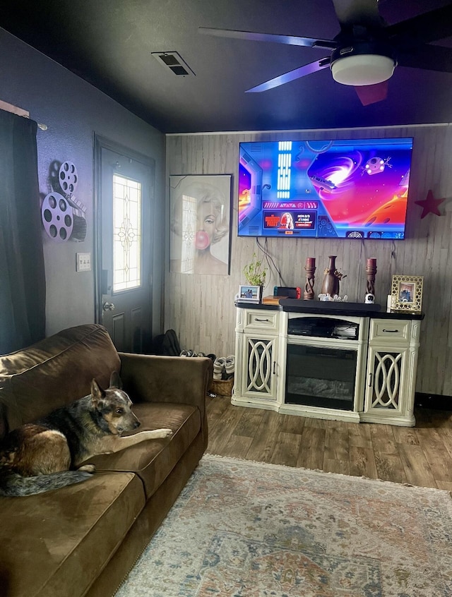 living room featuring wood finished floors, a ceiling fan, and wood walls