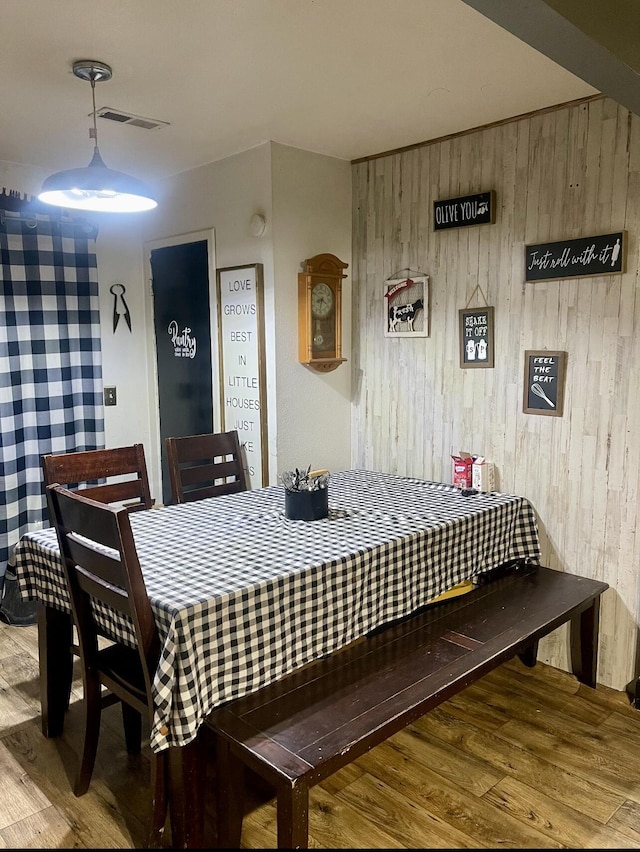 dining space with wooden walls and wood finished floors