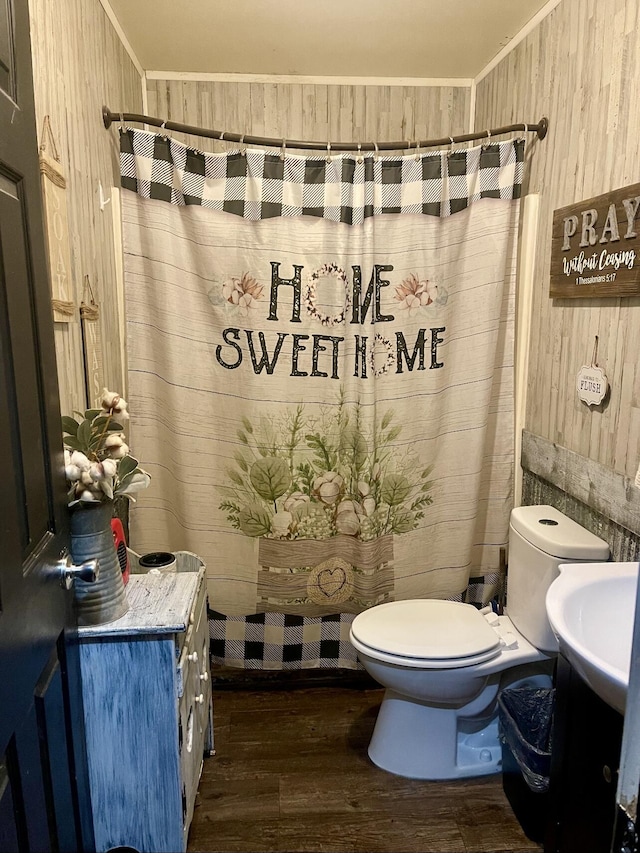 full bathroom featuring wooden walls, crown molding, wood finished floors, toilet, and a shower with shower curtain