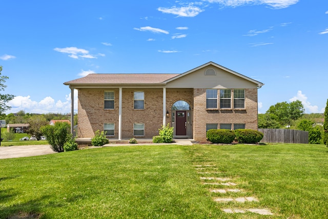 split foyer home featuring brick siding, fence, and a front yard