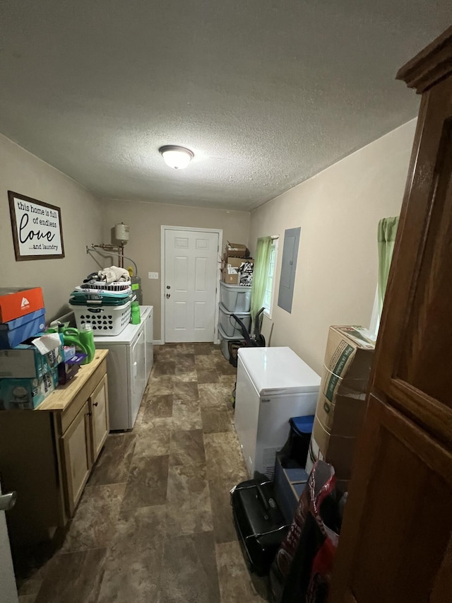 clothes washing area with a textured ceiling, electric panel, cabinet space, and independent washer and dryer