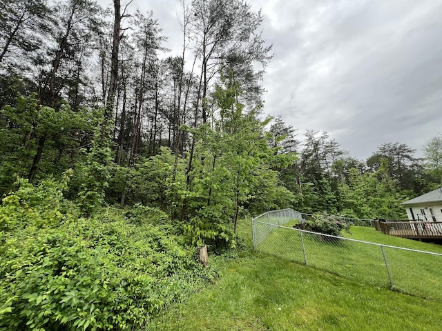 view of yard featuring fence, a deck, and a wooded view