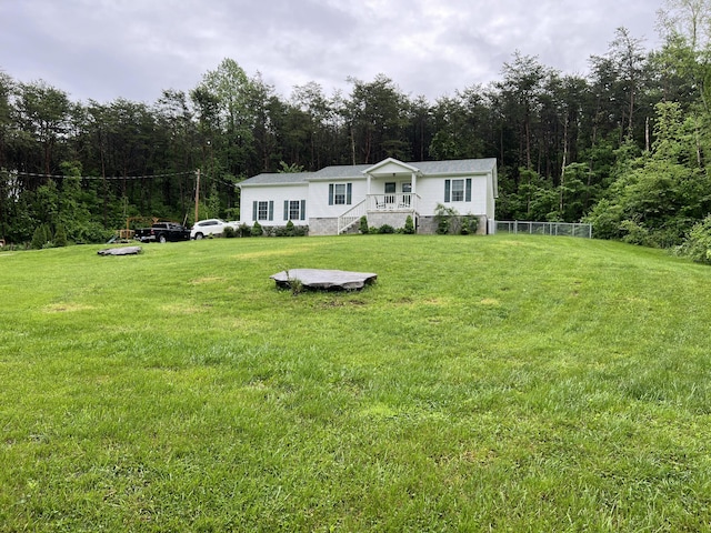 manufactured / mobile home featuring a view of trees and a front lawn