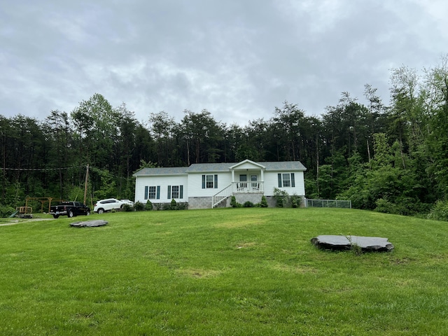 manufactured / mobile home with a wooded view and a front yard