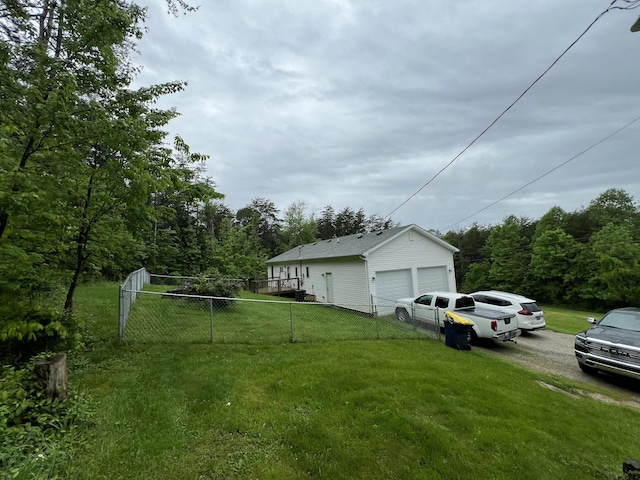 view of yard with fence, a detached garage, and a forest view