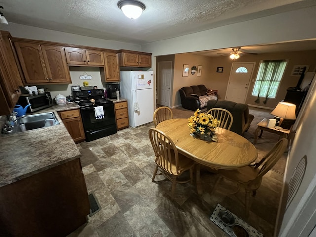 kitchen with freestanding refrigerator, black electric range oven, ceiling fan, stainless steel microwave, and a sink