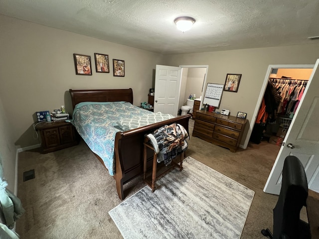carpeted bedroom with a closet, a textured ceiling, and a walk in closet