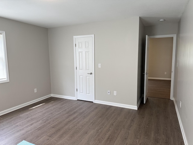 spare room with baseboards and dark wood finished floors