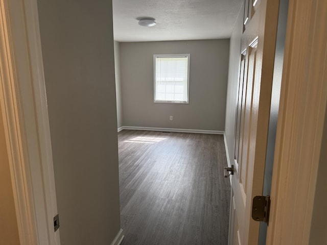 empty room featuring baseboards and dark wood finished floors