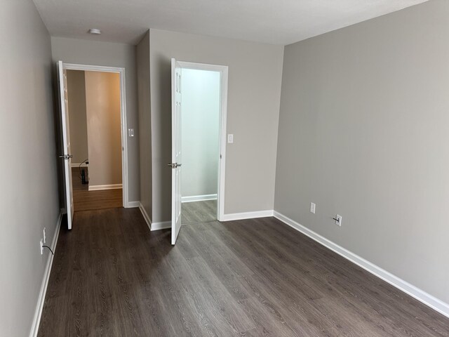 unfurnished bedroom with baseboards and dark wood finished floors