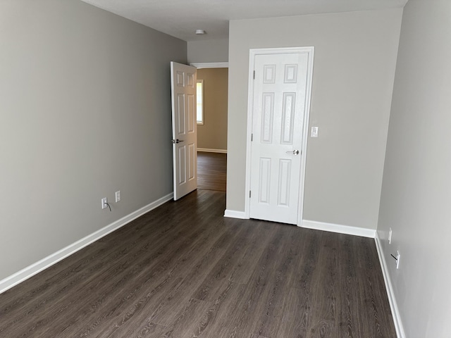 spare room featuring baseboards and dark wood finished floors