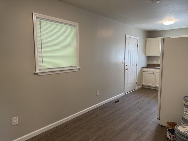 interior space with baseboards, dark wood-style flooring, and visible vents