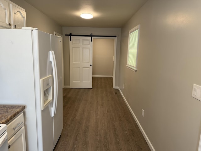kitchen with white fridge with ice dispenser, white cabinetry, a barn door, and dark wood-type flooring