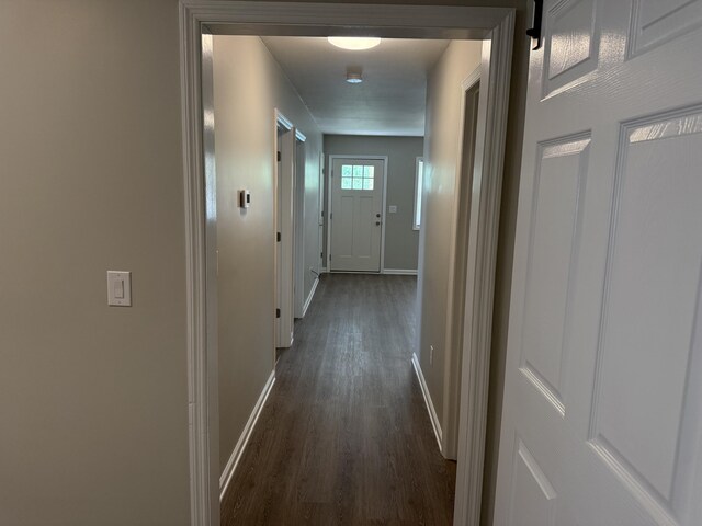 hall featuring baseboards and dark wood-style flooring