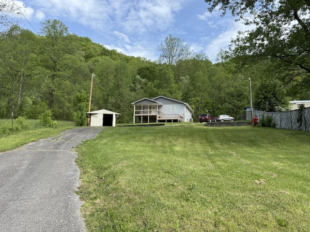 view of front facade featuring an outbuilding, a wooded view, a front lawn, and a garage