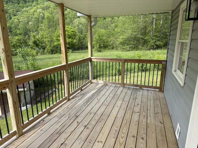 wooden terrace featuring a yard and a forest view