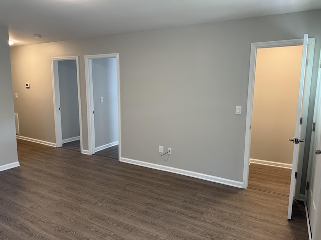 spare room with dark wood-type flooring and baseboards