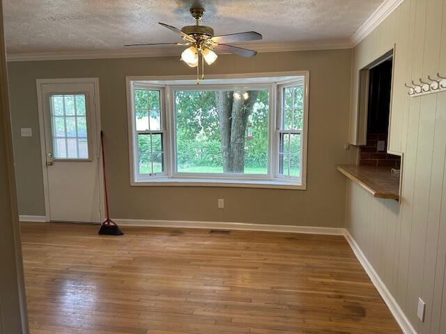 unfurnished dining area with light wood-style floors, a textured ceiling, ceiling fan, and baseboards