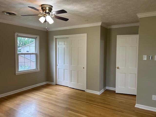 unfurnished bedroom with a closet, baseboards, visible vents, and light wood-style floors