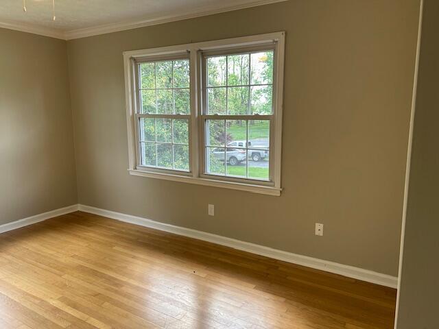 empty room with baseboards, ornamental molding, and hardwood / wood-style floors
