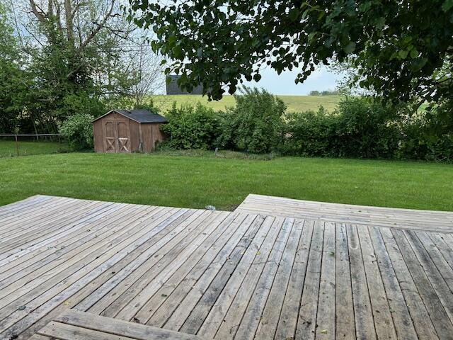wooden deck with a storage shed, fence, an outbuilding, and a yard