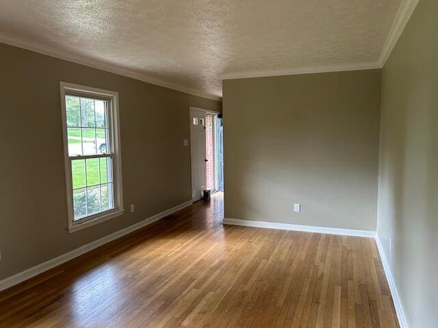 unfurnished room with baseboards, a textured ceiling, crown molding, and hardwood / wood-style floors