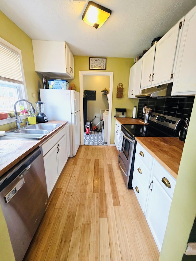kitchen with a sink, wood counters, white cabinets, and stainless steel appliances