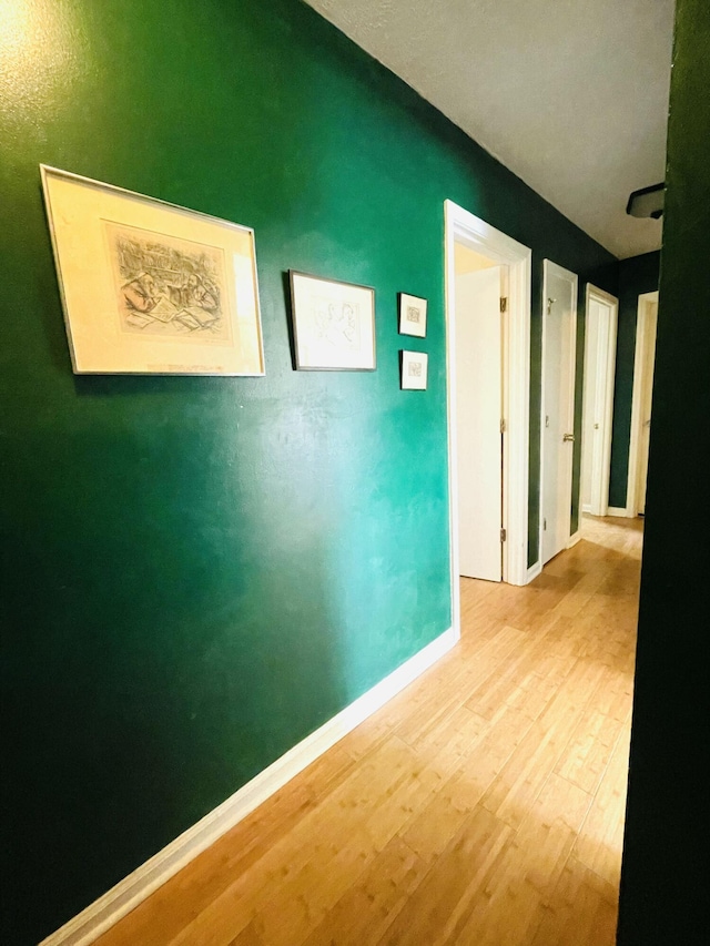 corridor featuring baseboards and wood finished floors