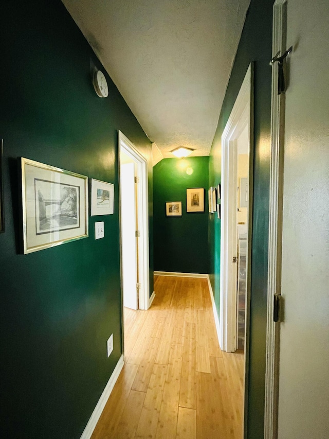 corridor with baseboards and light wood-style floors