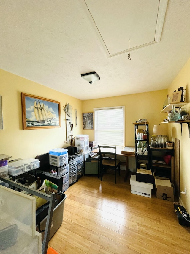 home office featuring light wood finished floors and attic access