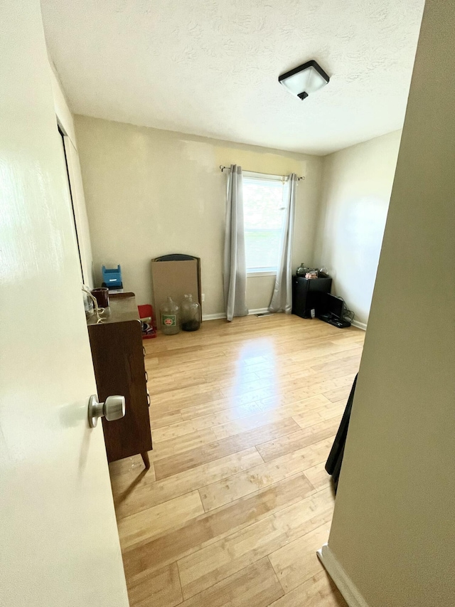 spare room with light wood-style floors and a textured ceiling