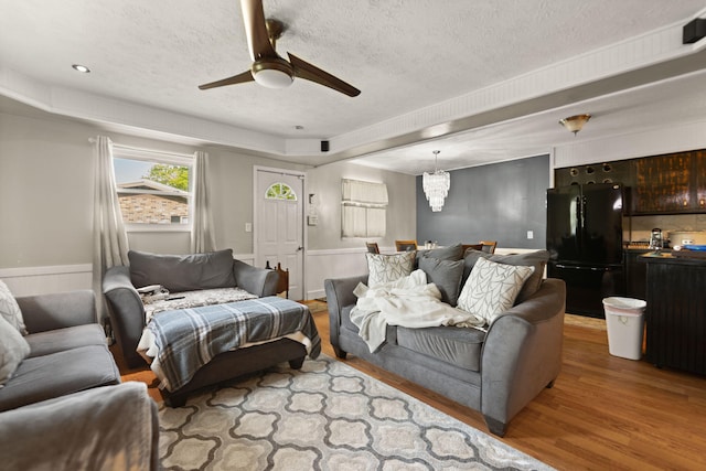 88 Plum St, Stanton, KY 40380 - living room featuring wood finished floors, a textured ceiling, a ceiling fan, a tray ceiling, and a chandelier
