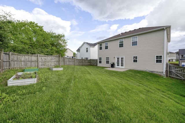 back of property with french doors, a vegetable garden, and a patio area