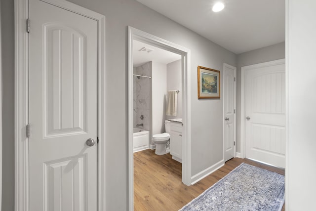 hall with light wood-type flooring, visible vents, and baseboards